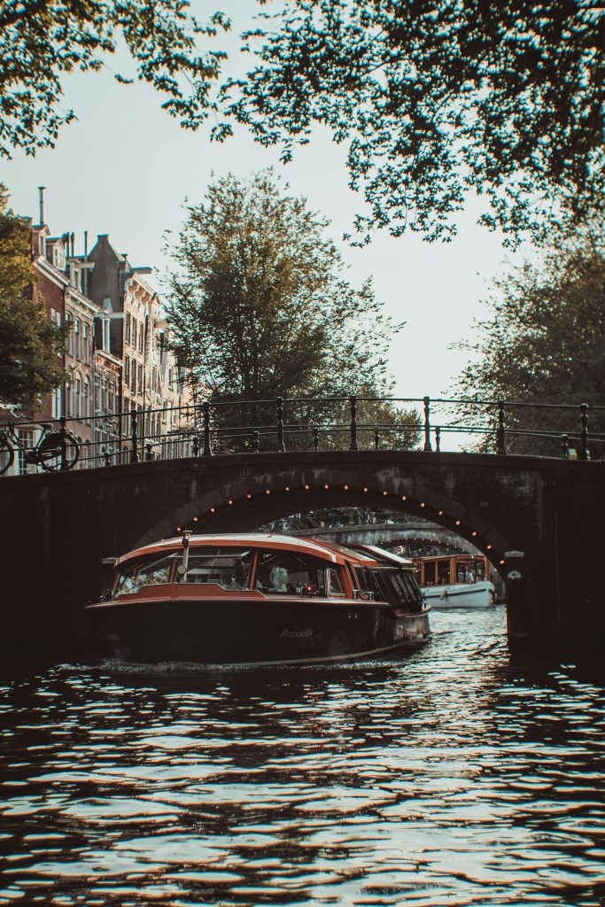 Experience a picturesque boat cruise under a historic bridge in Amsterdam's canal.